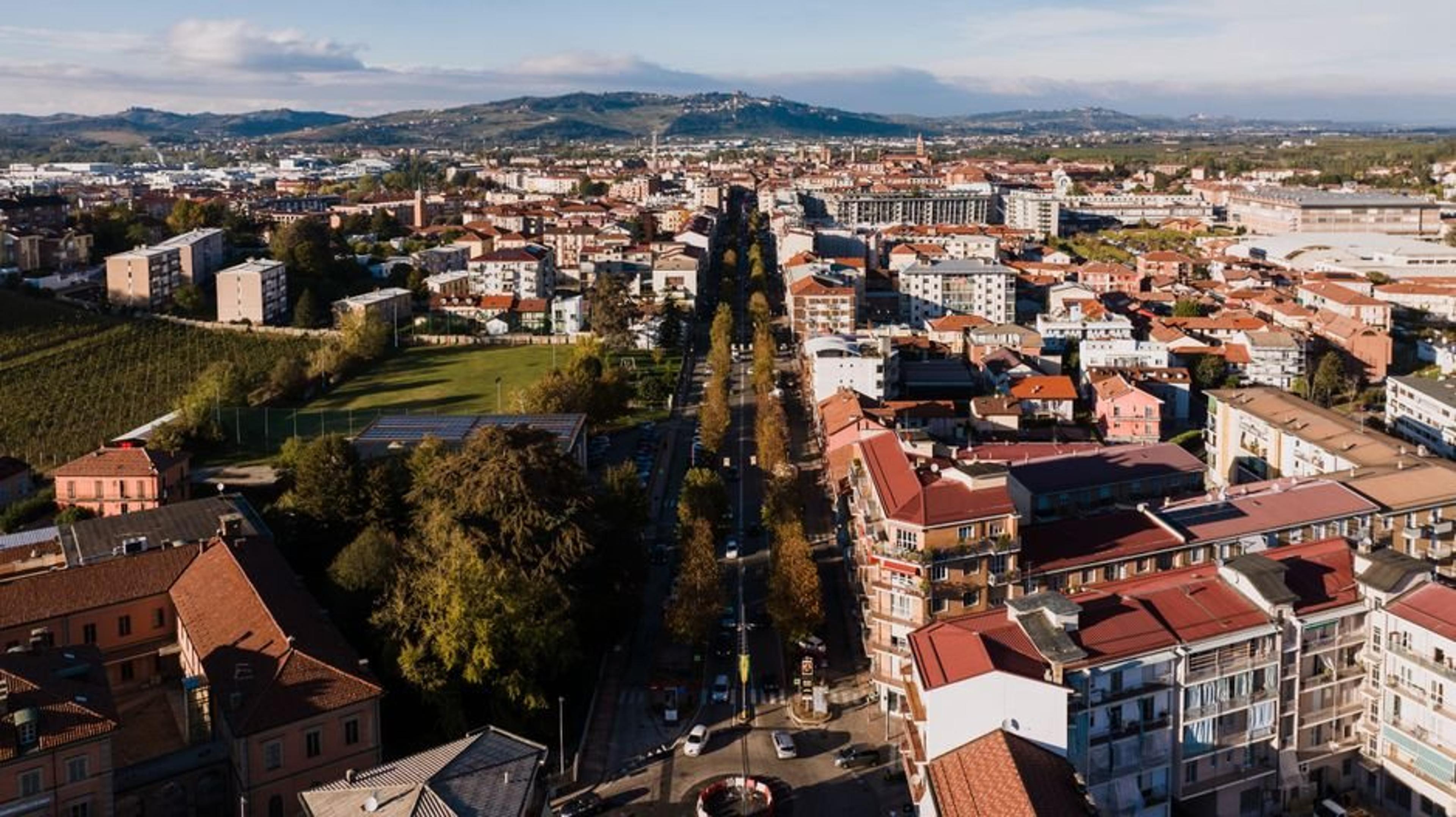 Aerial perspective of Alba's residential area in Italy, lined with trees and hills.